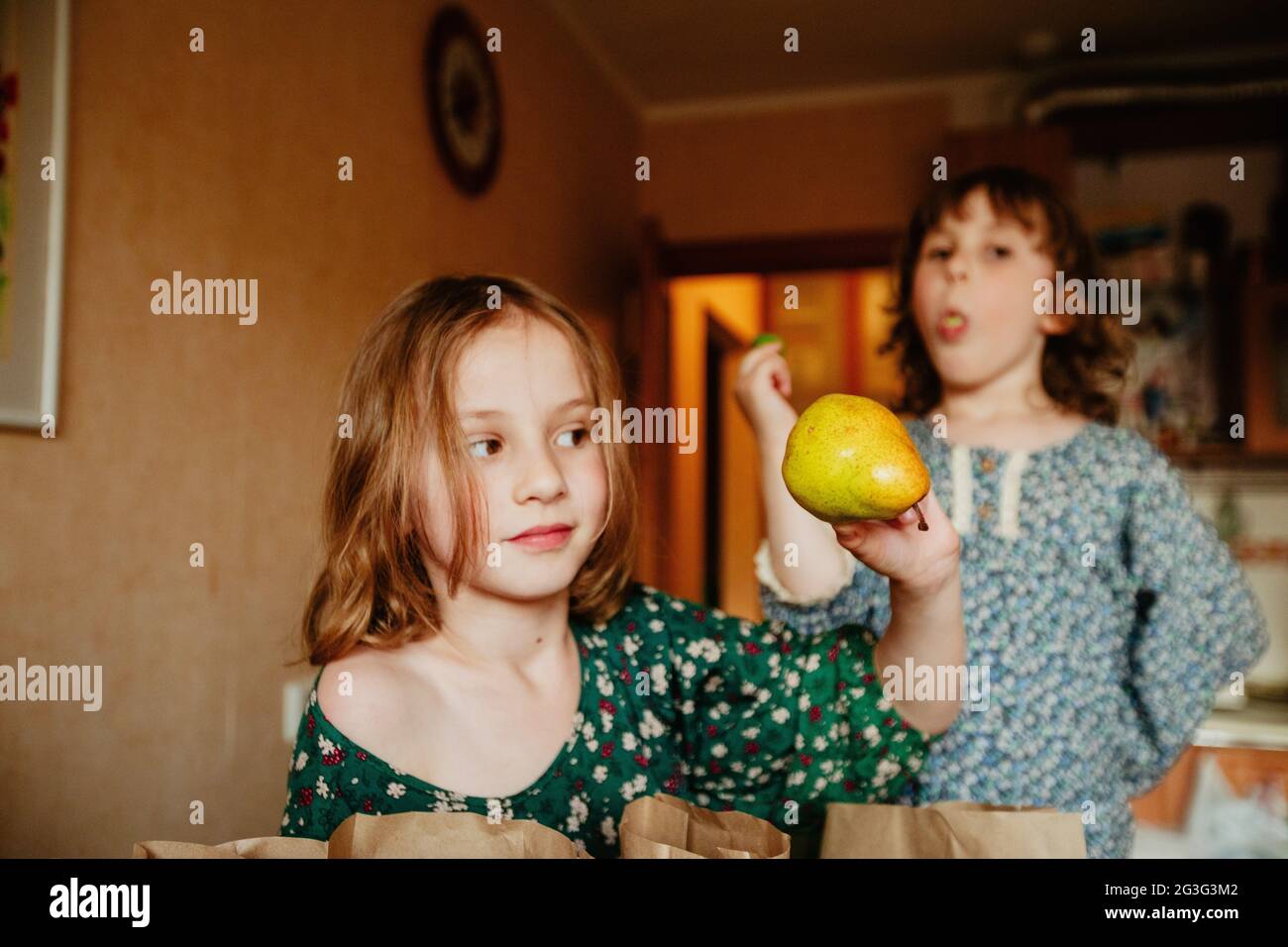 Enfant mignon avec poire verte mûre dans la cuisine montrant le concept de nourriture saine Banque D'Images