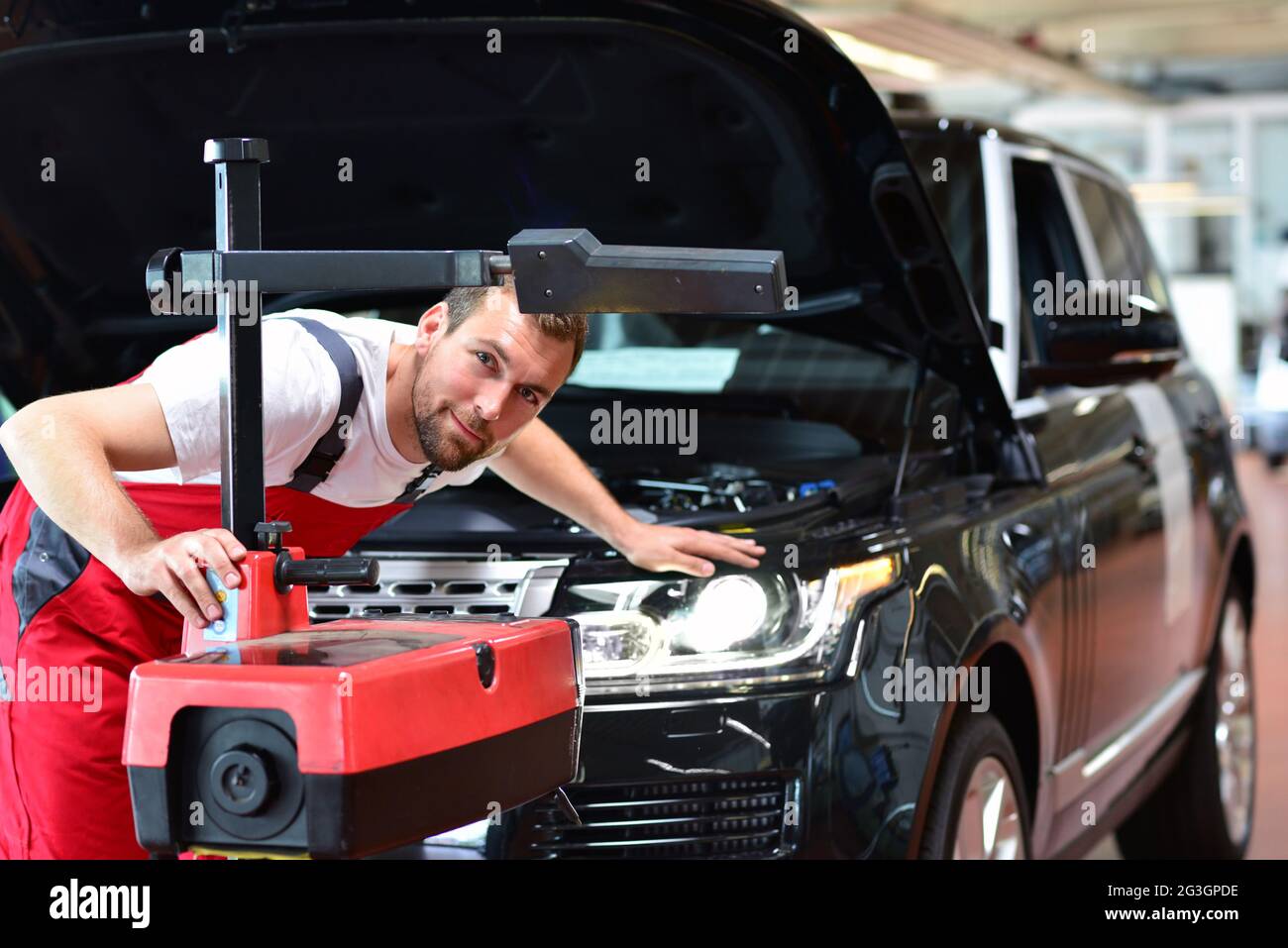 Atelier de réparation automobile - travailleur vérifie et ajuste les phares d'un système d'éclairage de voiture Banque D'Images