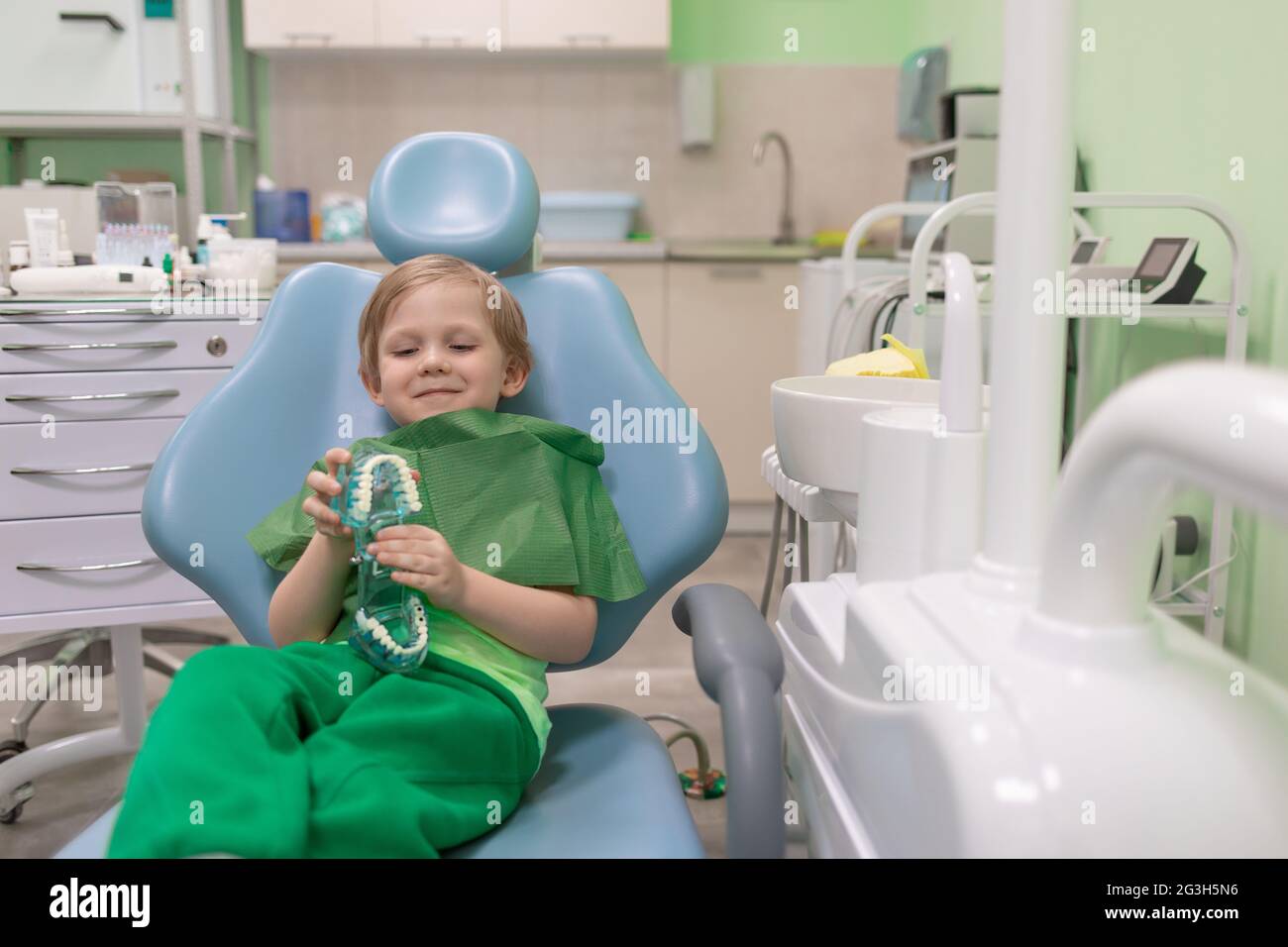 Un enfant de race blanche s'assoit dans une chaise dentaire chez un dentiste. Préchooler traitant les dents, heureux. Concept publicitaire avec espace de copie. Banque D'Images