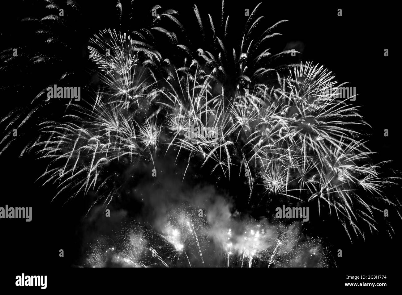 Feux d'artifice blancs étincelants dans un ciel noir. Photographie en noir et blanc. Banque D'Images
