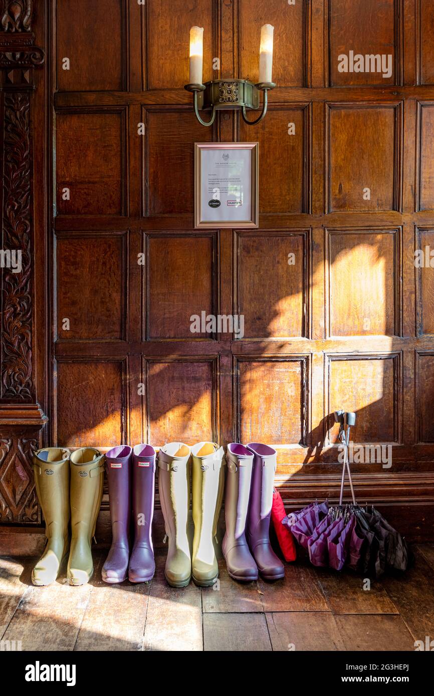 Bottes en caoutchouc et parasols à l'entrée de l'hôtel Manor House, Castle Combe, Wiltshire, Angleterre, Royaume-Uni Banque D'Images