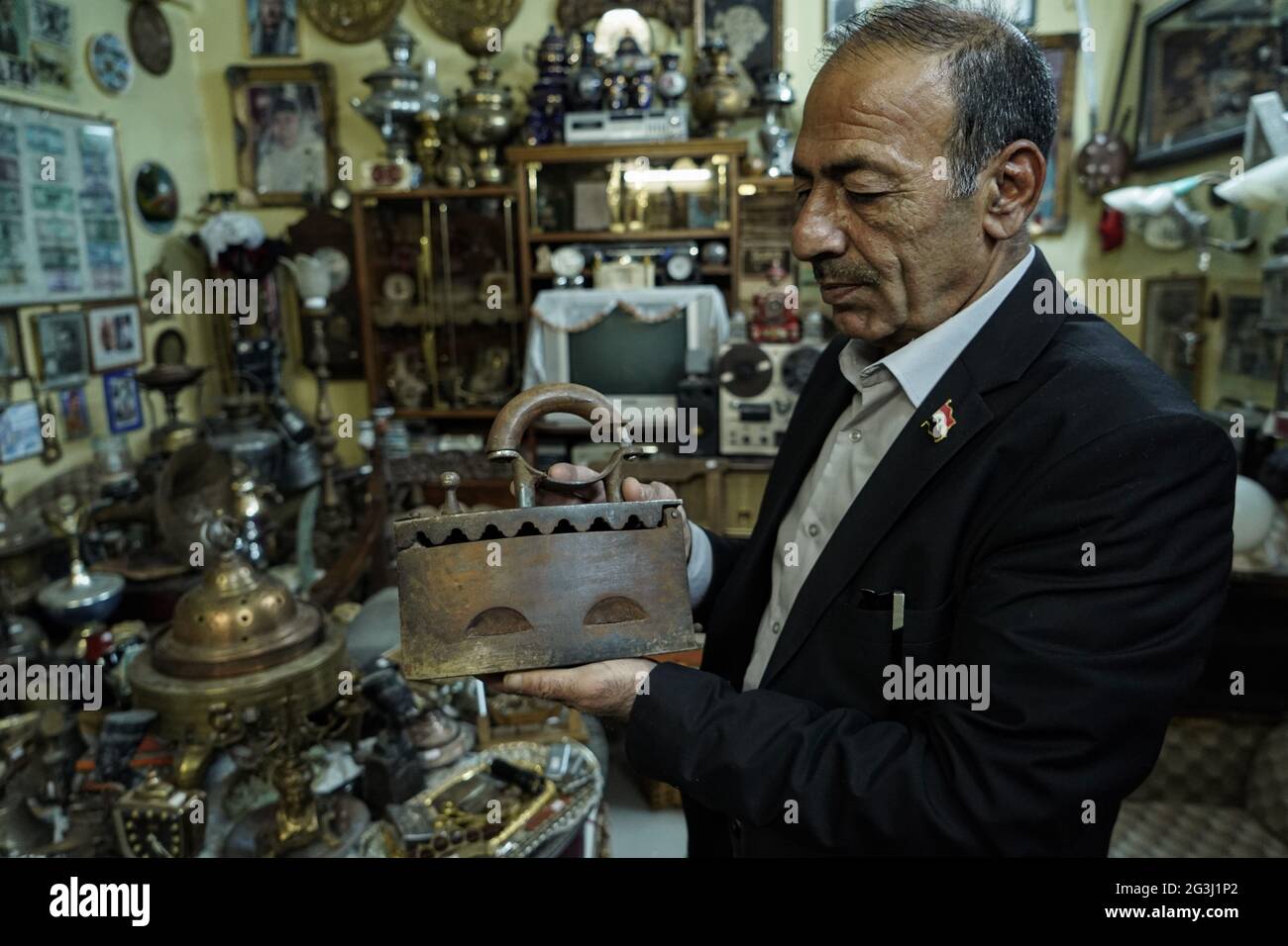 16 juin 2021, Irak, Mossoul: L'irakien Fakhri Suleiman Al-Tai tient un ancien fer à charbon de bois dans le cadre d'une collection de pièces anciennes qu'il a rassemblées après son retour dans la vieille ville de Mossoul après sa libération de la soi-disant organisation terroriste de l'État islamique (EI). Al-Tai a décidé de convertir sa maison en musée temporaire où il expose plus de 5,000 pièces reflétant l'héritage et l'histoire de Mossoul, qui a été gravement endommagé entre 2014 et 2017 sous le règne de l'État islamique. Al-Tai a dépensé près de 33,000 dollars US à la poursuite de sa passion de recueillir et de préserver la tarte Banque D'Images