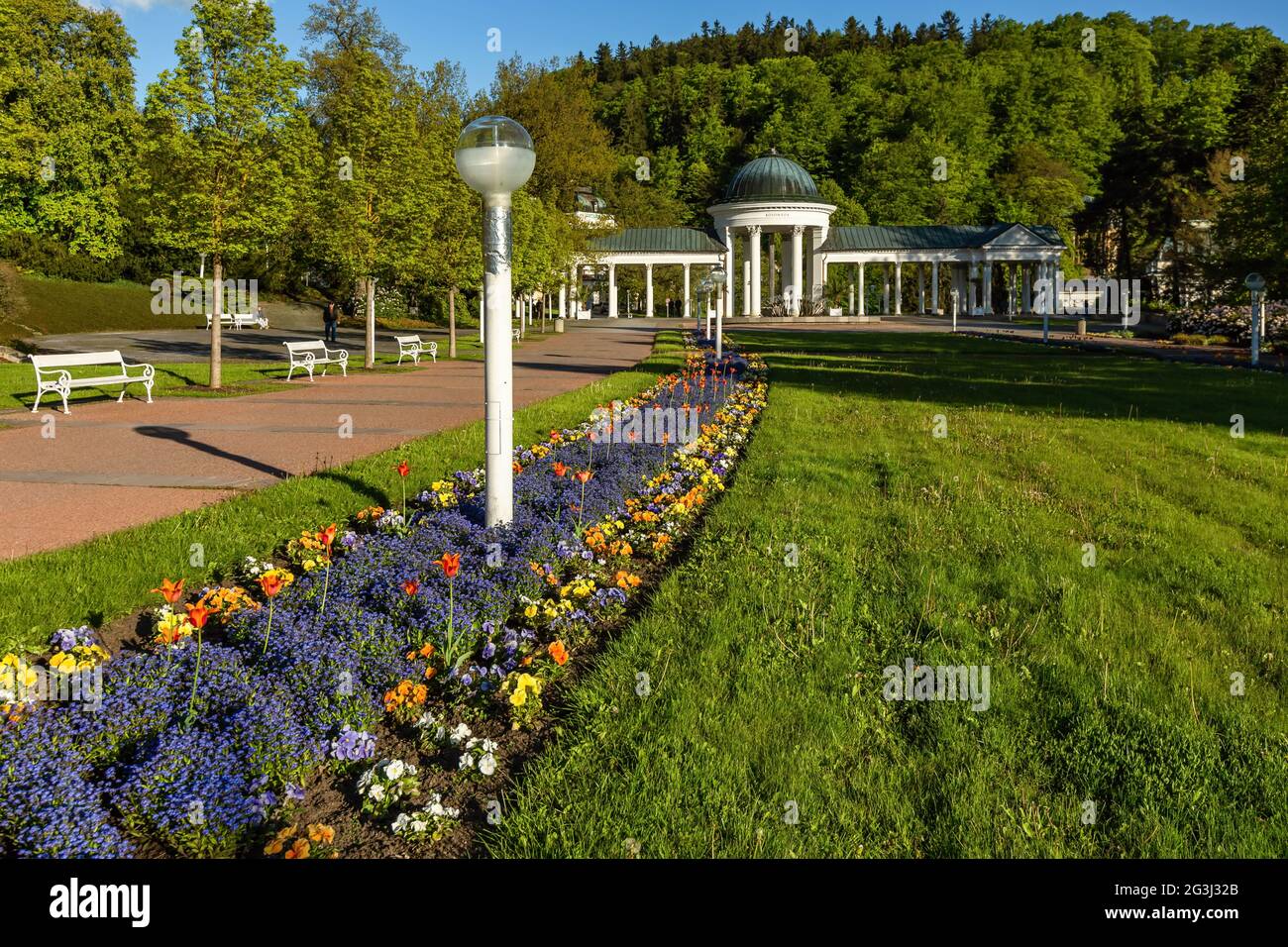 Marianske Lazne, République tchèque - Mai 30 2021 : vue sur le pavillon blanc de la source minérale. Pelouse verte et lit de fleur coloré au premier plan. Banque D'Images