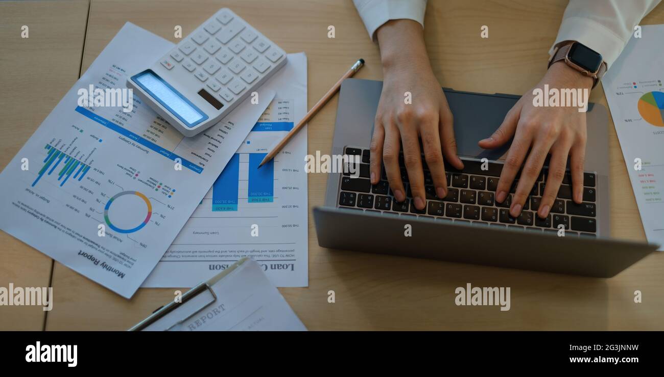 Business femme Trader investisseur utilisant ordinateur portable avec paperasserie du marché des actions sur le bureau. Graphique des actions, concept d'investissement. Banque D'Images