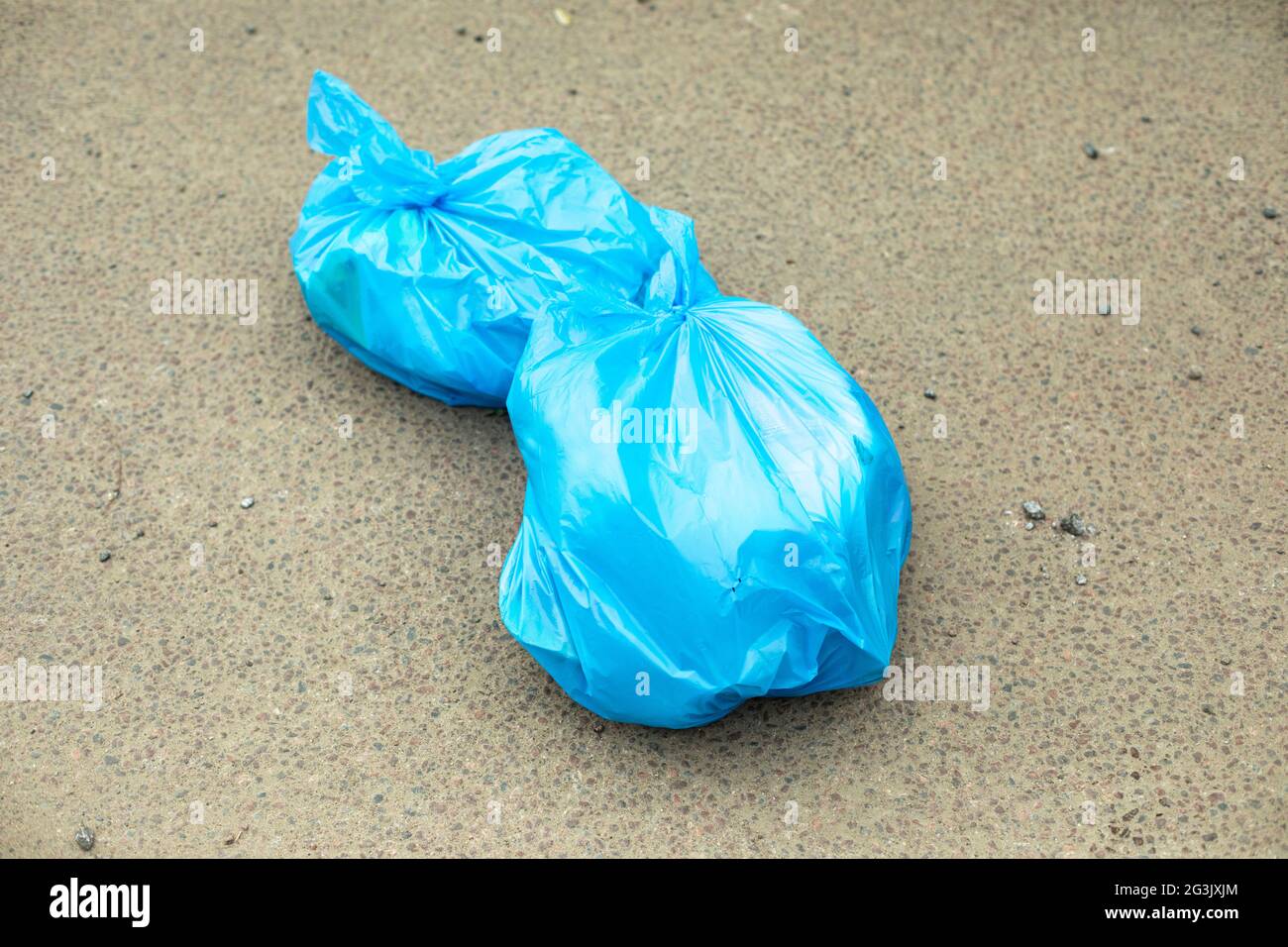 Sac poubelle sur la route. Un sac poubelle bleu repose sur l'asphalte. Les déchets ménagers sont jetés au mauvais endroit. Banque D'Images