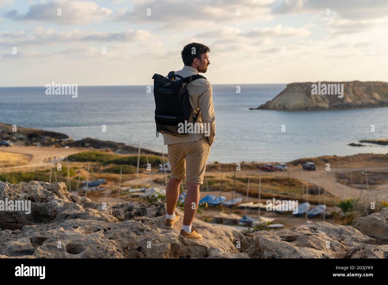 Mâle touriste avec sac à dos regarder la belle vue de Yeronisos Sainte île  près de la côte Agios Georgios Pegeias à Chypre sur le coucher du soleil.  Look de randonneur d'homme