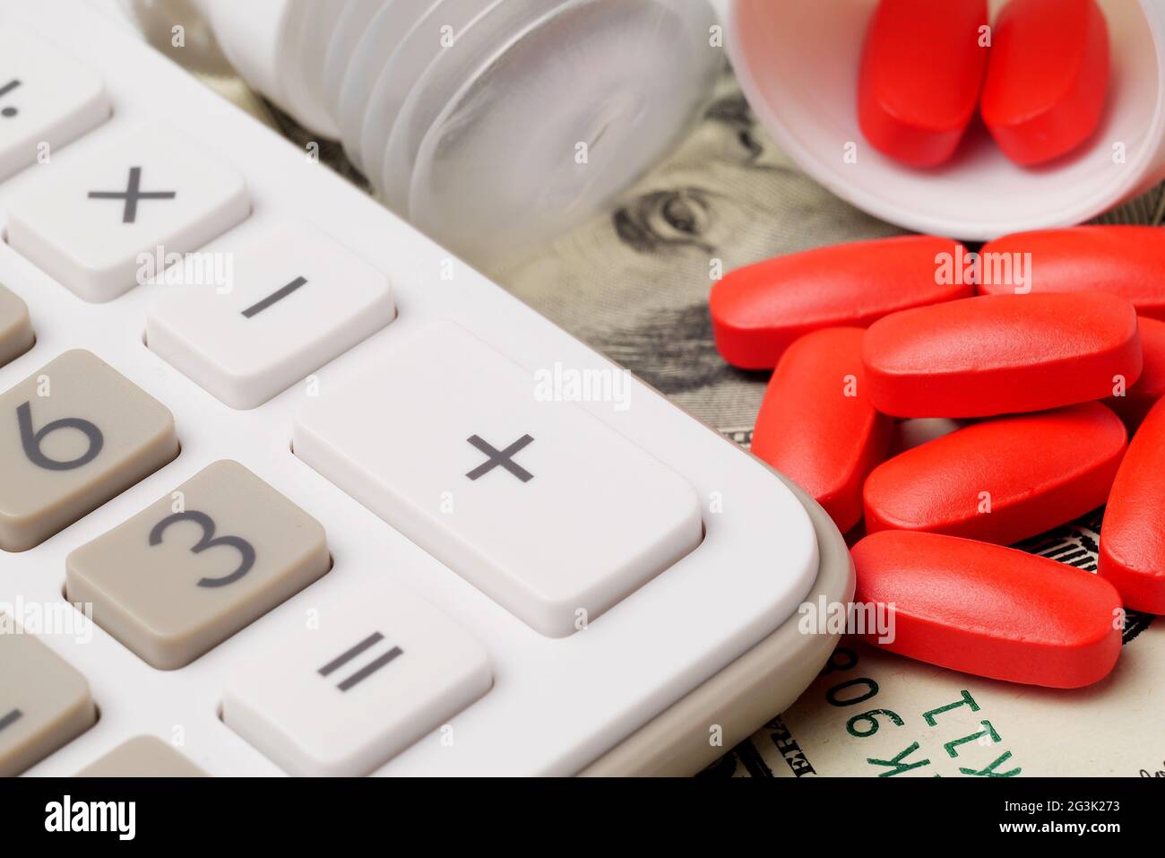 Macro-vision de calculatrice, pilules rouge renversé et billets de dollar, concept pour les frais médicaux Banque D'Images