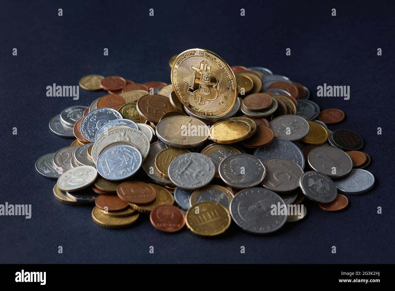 Des pièces de monnaie en bitcoin dorées et brillantes en plus des différentes monnaies du monde, représentant un choix de différentes options de paiement et d'investissement. Banque D'Images
