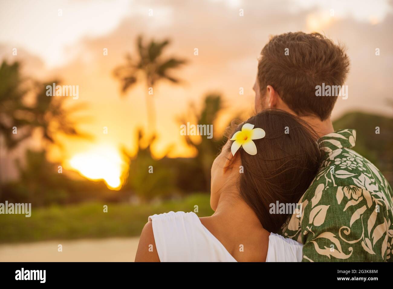Couple romantique se détendant en regardant le coucher du soleil sur la plage promenade vue de l'arrière. Femme se reposant la tête sur l'épaule de l'amant lors d'un voyage de vacances en lune de miel en été Banque D'Images