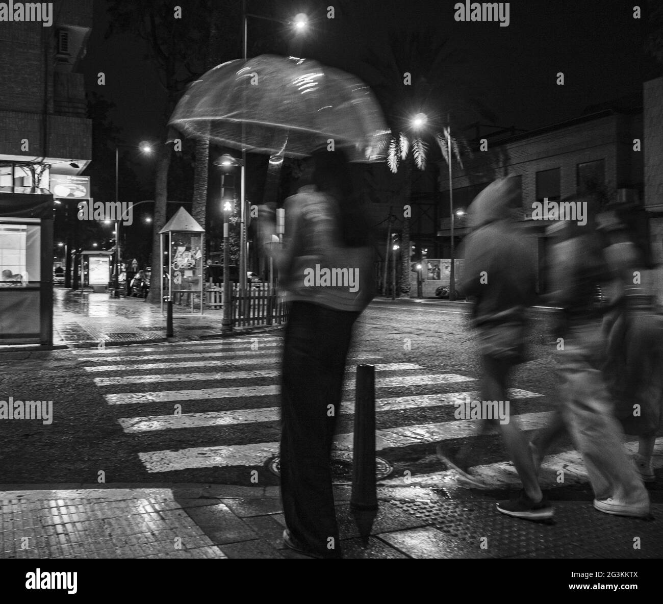 Photo en niveaux de gris des piétons qui marchent dans les rues la nuit Banque D'Images