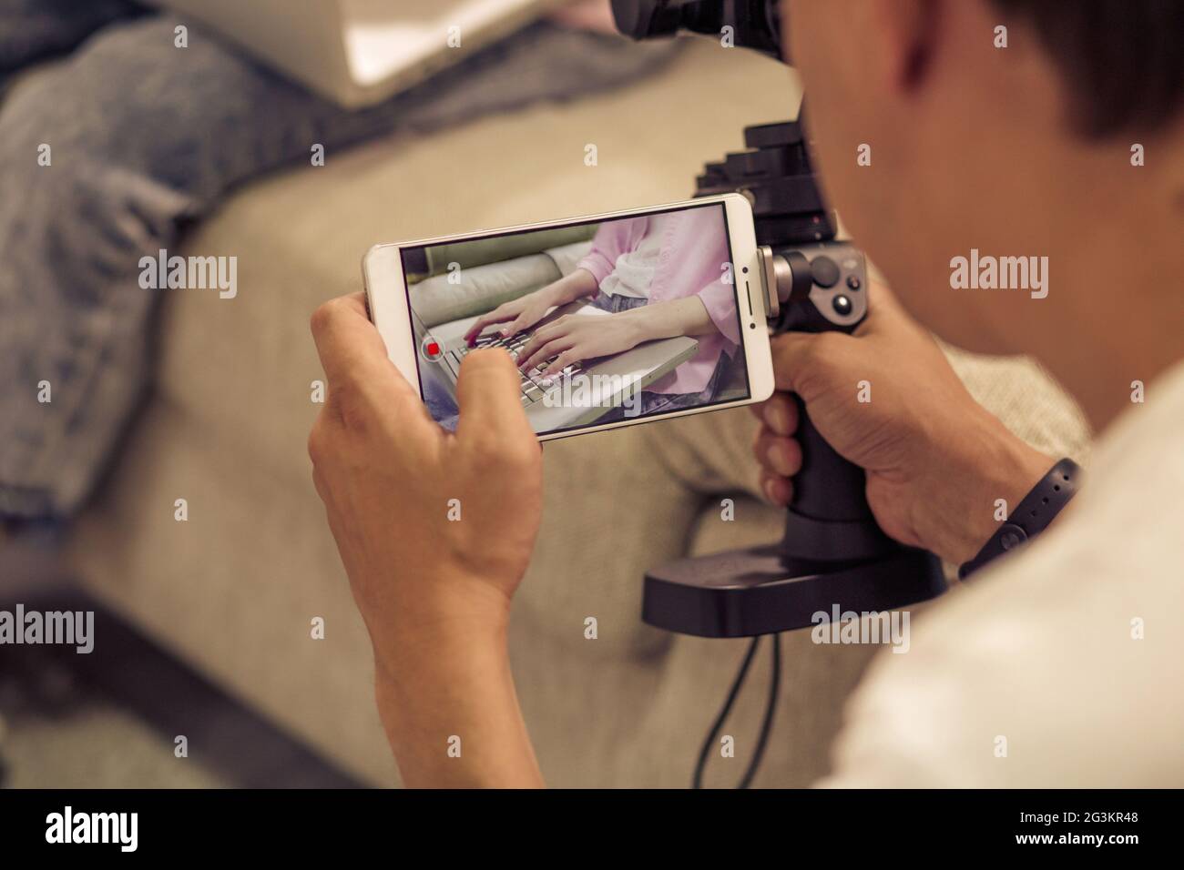 Homme de tir fille dactylographiant sur ordinateur portable avec appareil photo de téléphone cellulaire. Banque D'Images