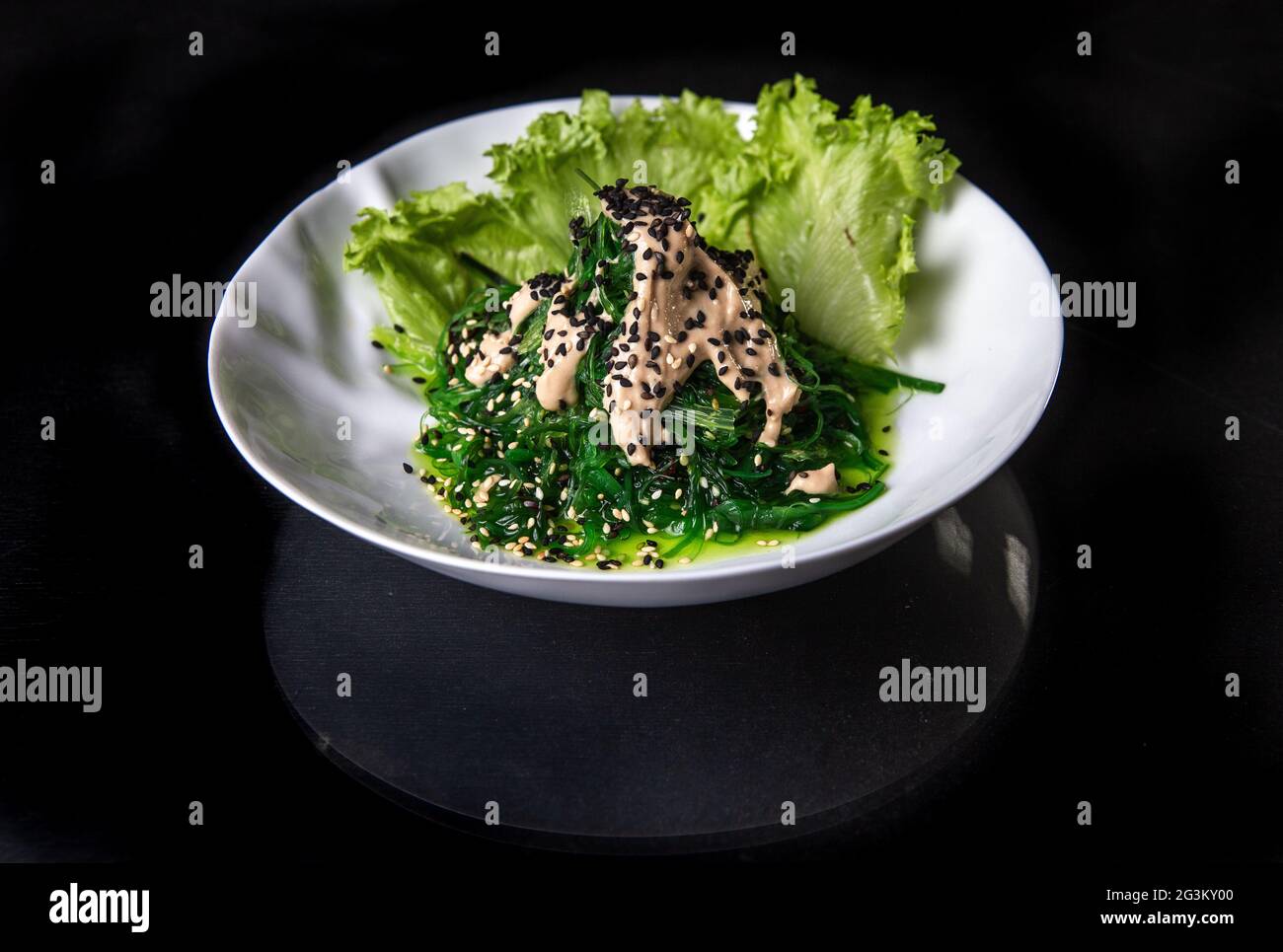 Salade japonaise dans une assiette blanche sur fond noir. Photos pour la conception du menu Banque D'Images