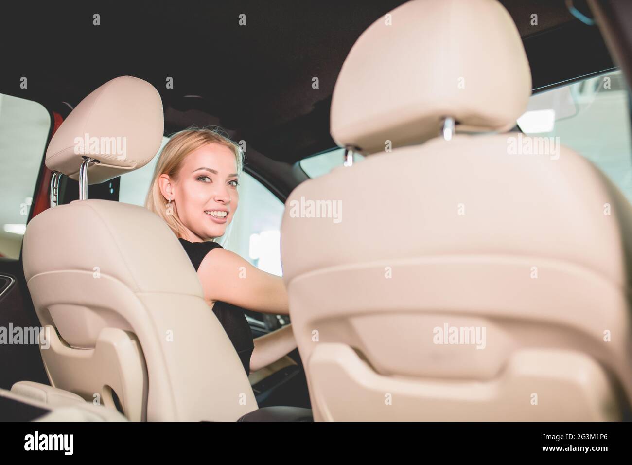 Jolie femme sur le siège avant de la nouvelle voiture dans la salle d'exposition automobile. Banque D'Images