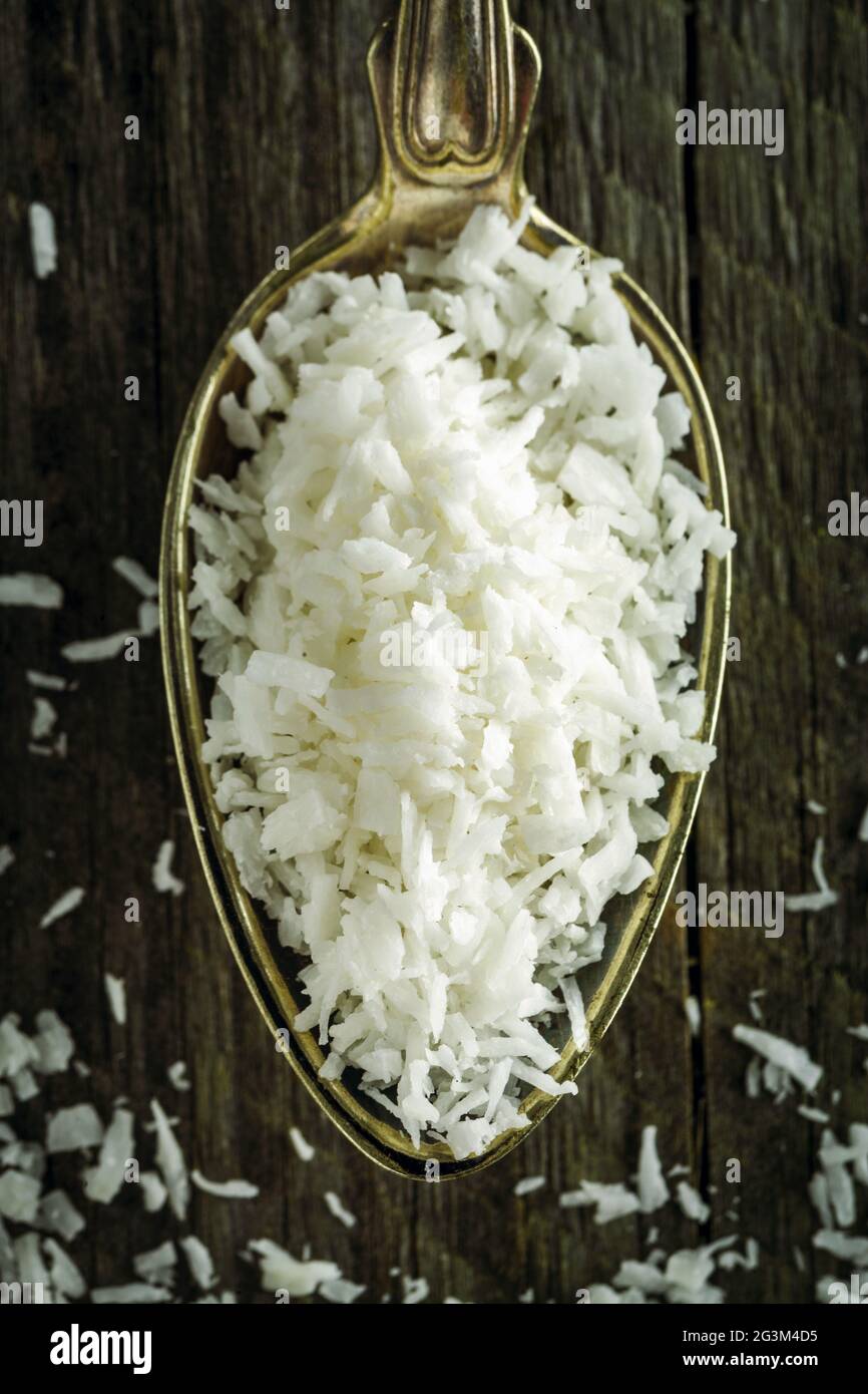 Cuillère à soupe de flocons de noix de coco desséchée sur un fond de bois Banque D'Images