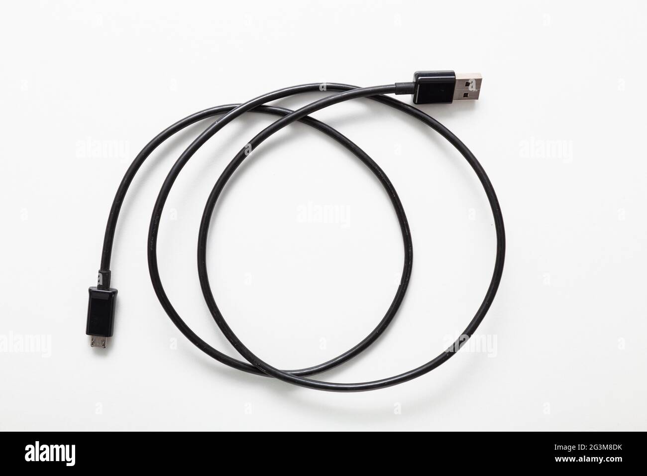 Câble noir spiralé avec connecteurs USB et micro USB isolés sur fond blanc. Banque D'Images