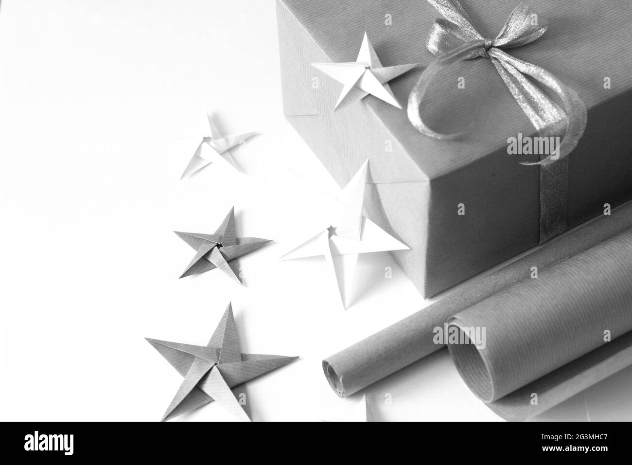 Emballage des cadeaux de Noël. Plat minimal de boîte cadeau, rouleaux de papier Kraft, étoiles Origami sur fond blanc. Concept de fête des fêtes. Banque D'Images
