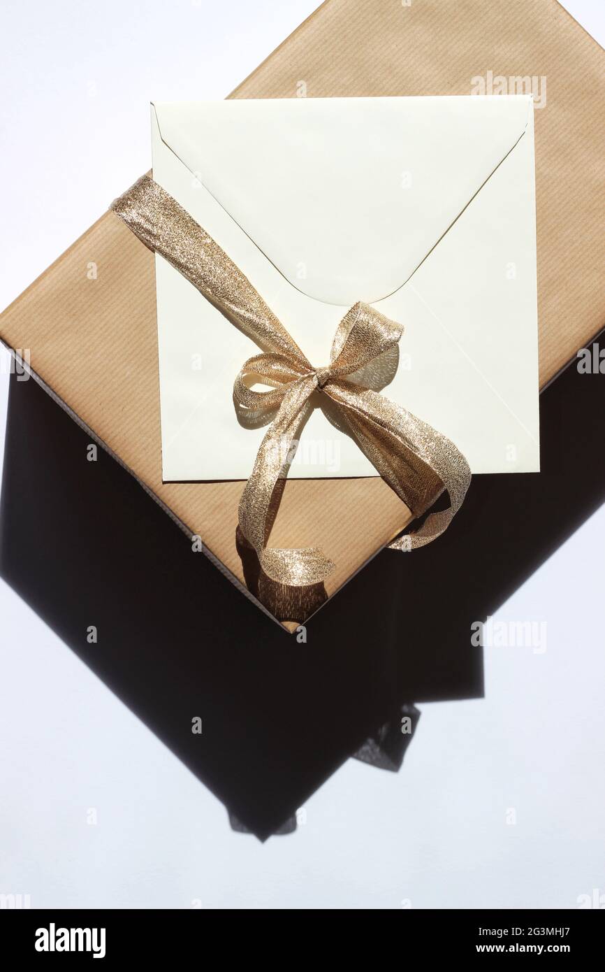 Boîte cadeau avec enveloppe décorée d'un noeud en ruban doré. Noël conception de vacances. Banque D'Images