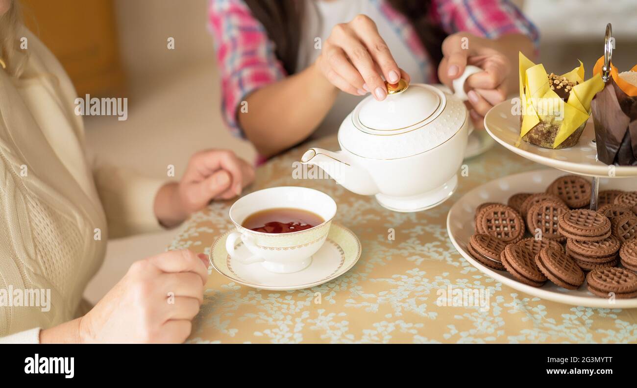 Les mains de la jeune femme avec la théière chinoise blanche versant du thé dans la tasse de sa mère âgée Banque D'Images