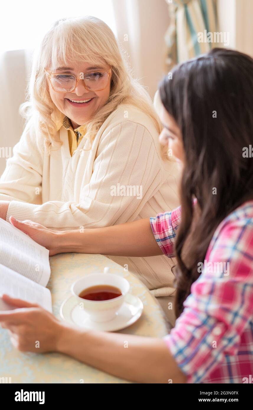 La mère et la fille ont lu un livre sur une tasse de thé Banque D'Images