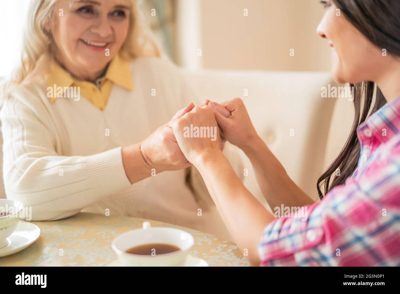 Mère âgée et sa fille se tenant les mains tout en étant assis à la table Banque D'Images