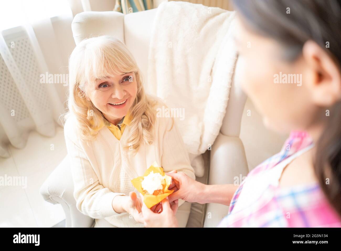 Charmante fille donne un petit gâteau d'anniversaire avec bougie à sa mère âgée Banque D'Images