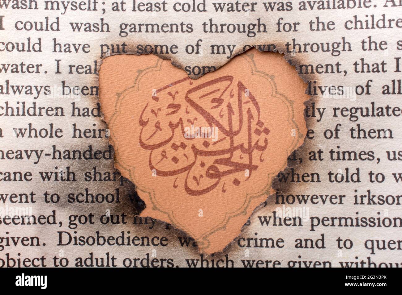 Trou en forme de coeur papier brûlé sur mots arabes Banque D'Images