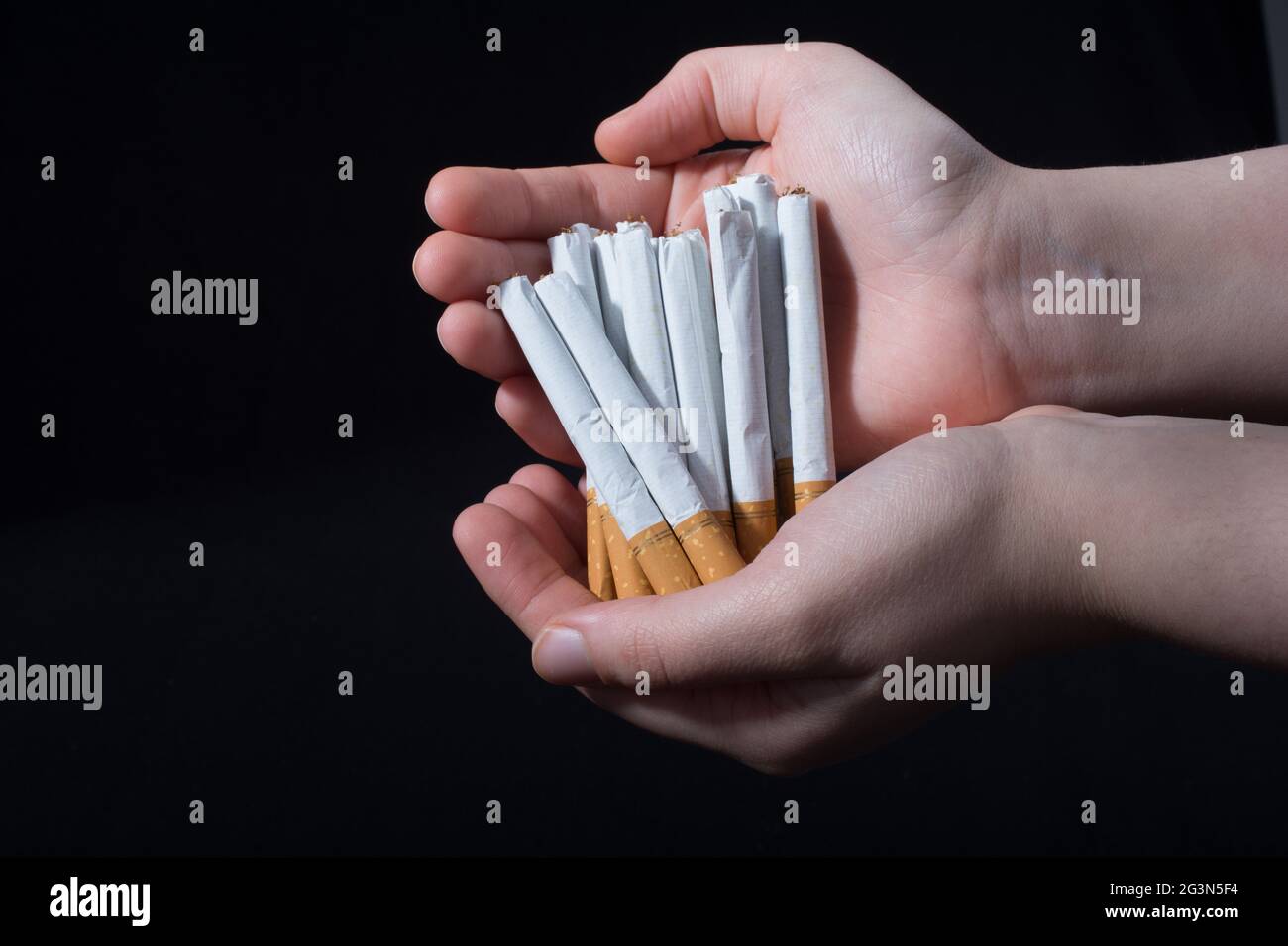 La main donne un paquet de cigarettes sur noir Banque D'Images