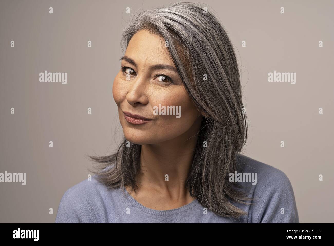 Un Silver-Haired femme Mongole regarde pensivement dans le cadre. Banque D'Images