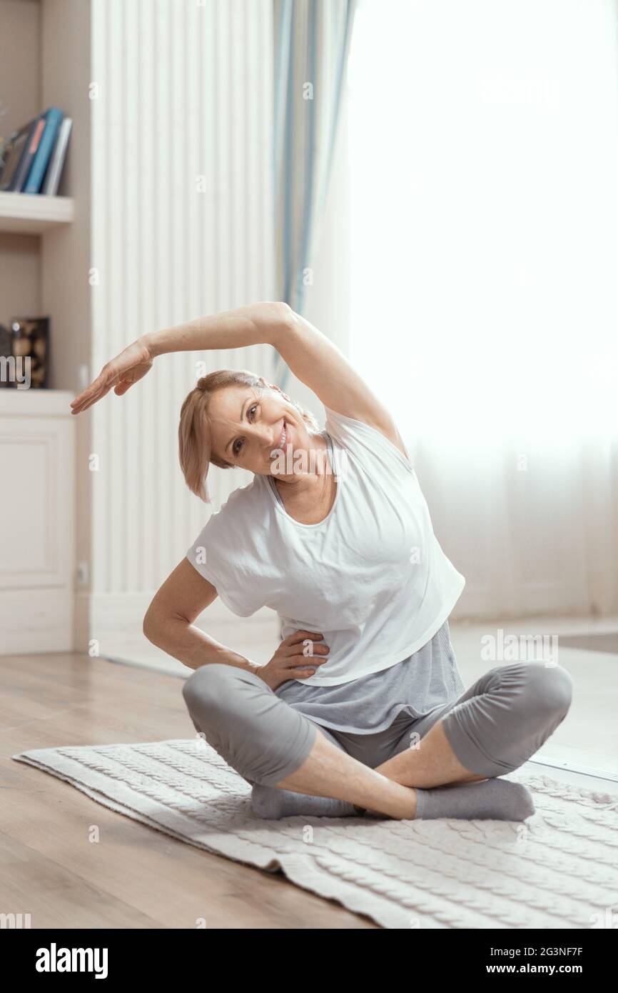 Des cours de yoga à la maison de belles femmes de plus de 50 ans. Banque D'Images