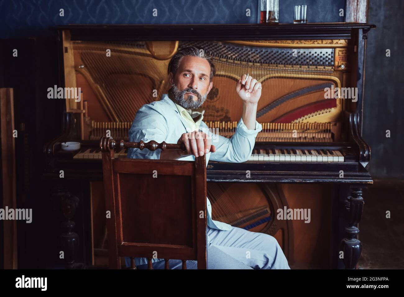 L'homme brutal, avec une barbe de 40 ans joue le vieux piano. Banque D'Images