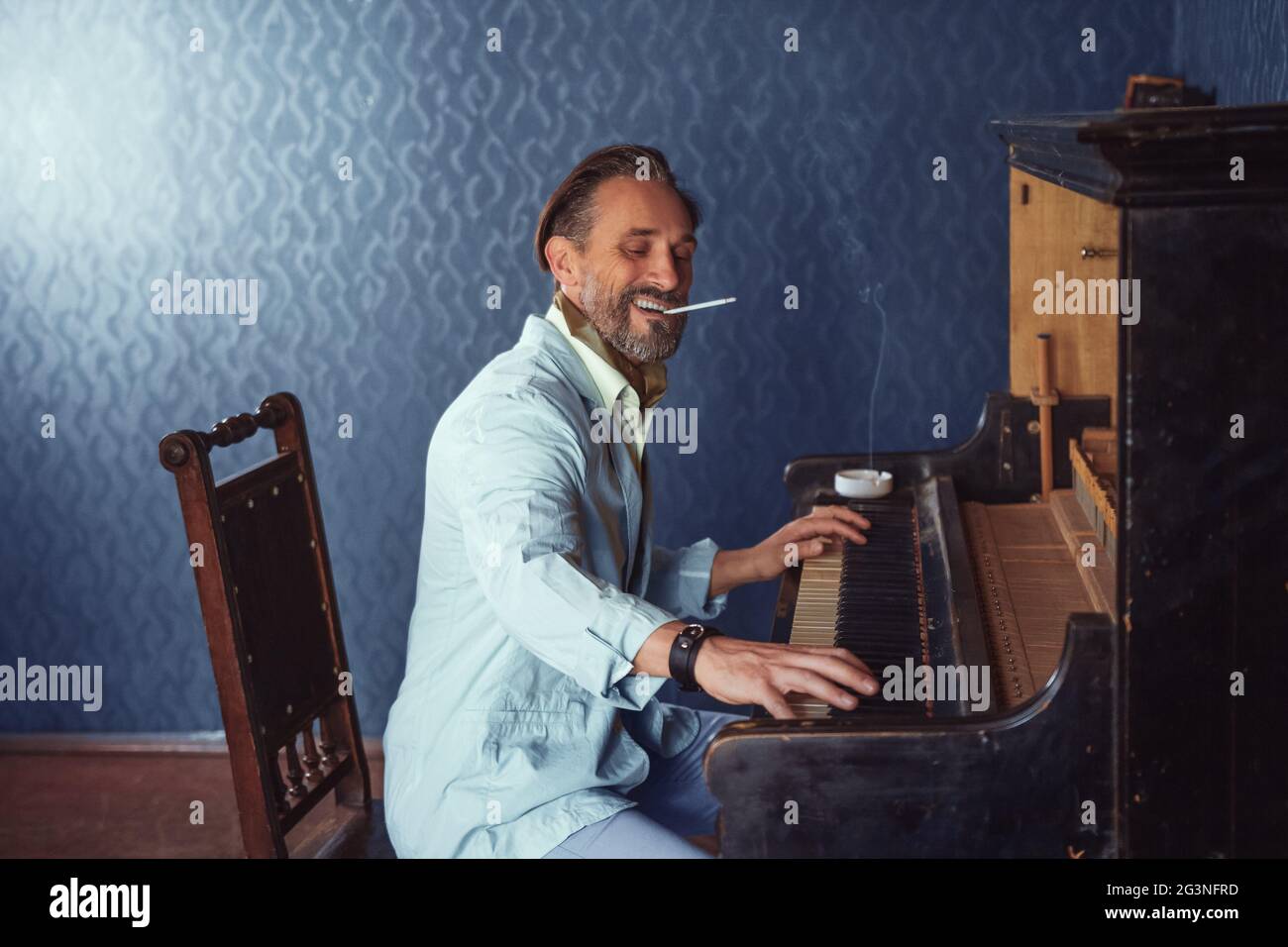 L'homme brutal, avec une barbe de 40 ans joue le vieux piano. Banque D'Images