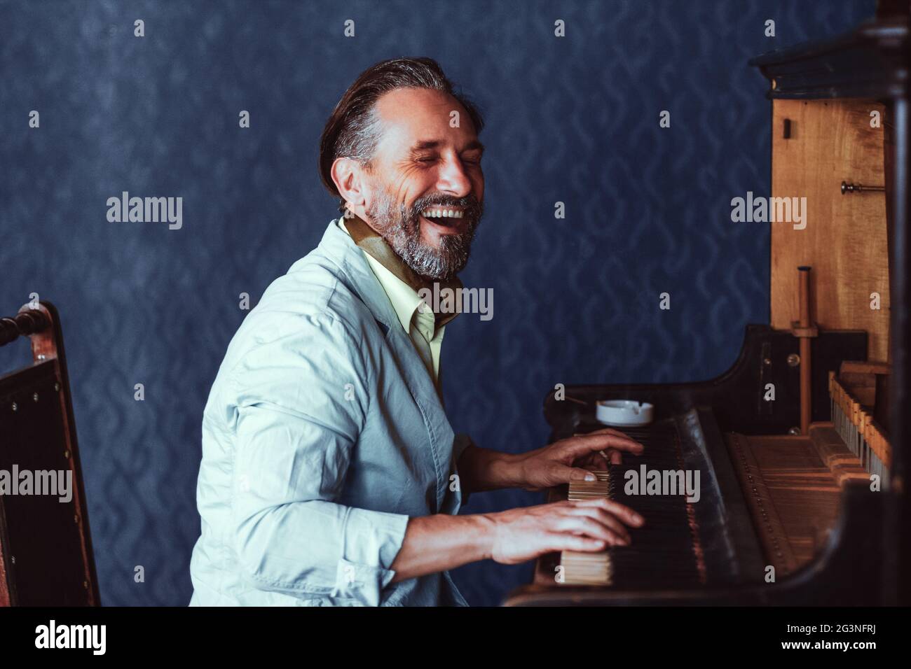L'homme brutal, avec une barbe de 40 ans joue le vieux piano. Banque D'Images