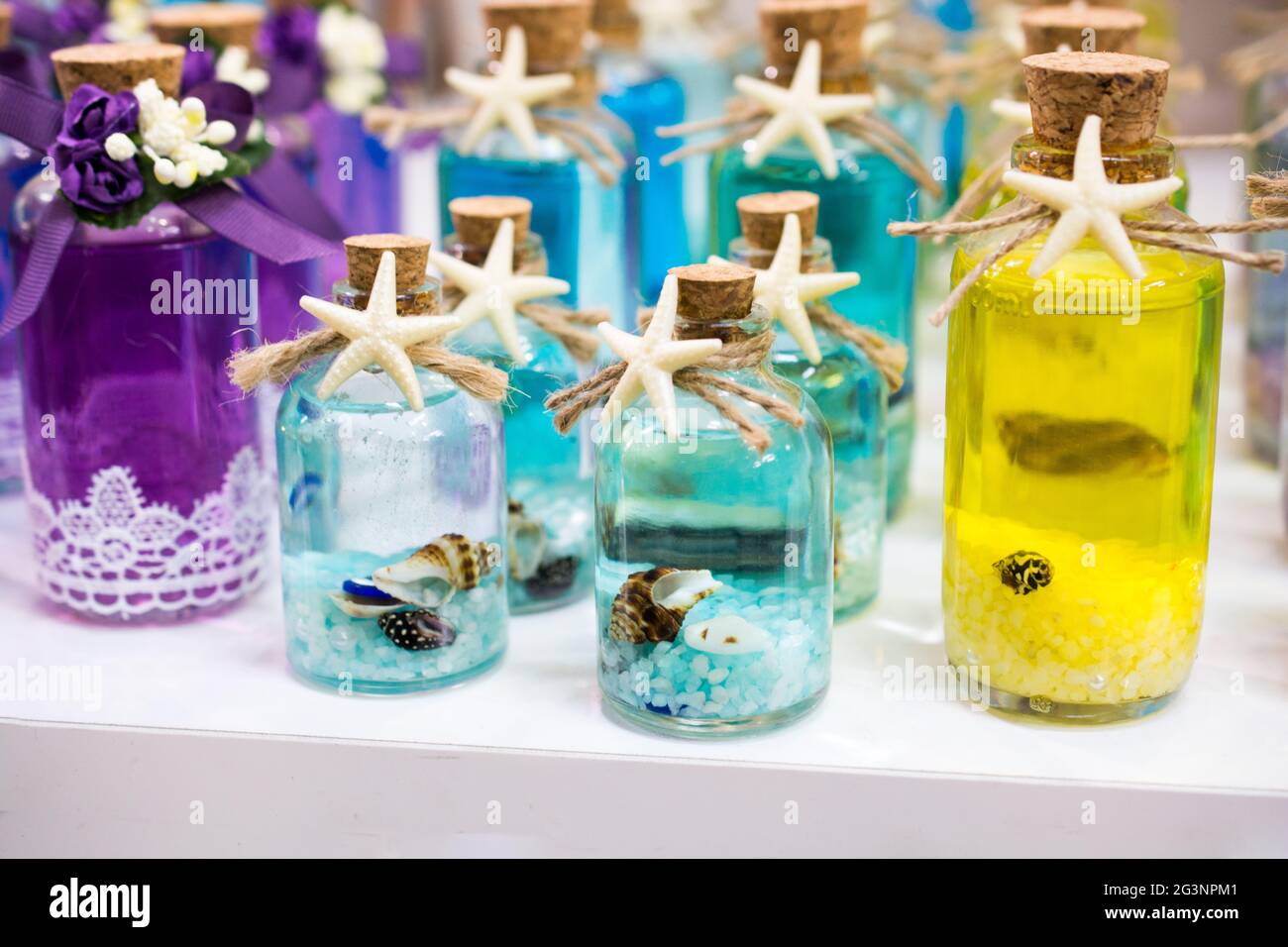 Jeu de petites bouteilles transparentes vides remplies de cailloux et de coquillages Banque D'Images
