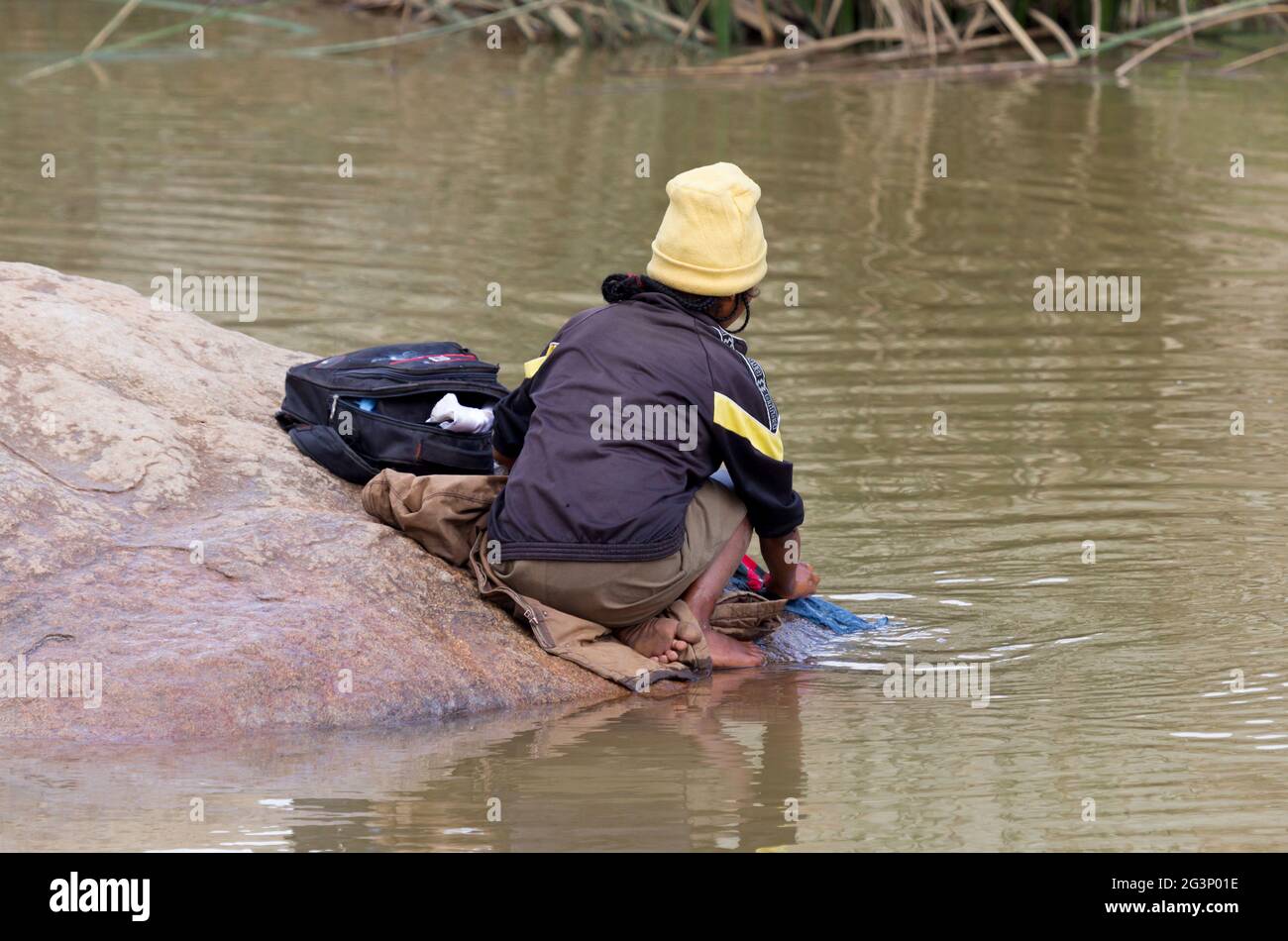 Femme méconnaissable faisant la lessive dans une rivière Banque D'Images