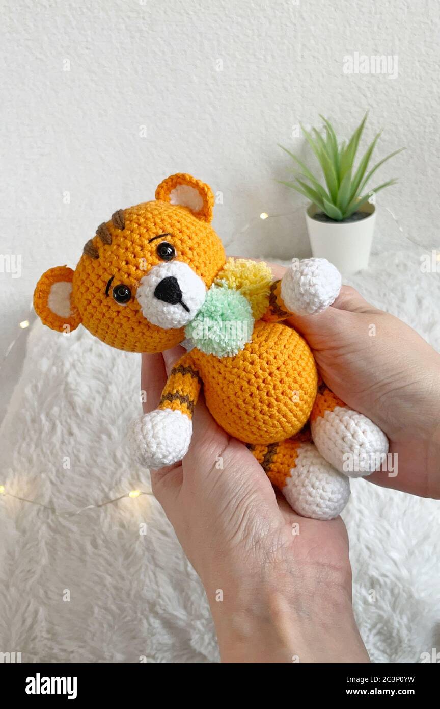 Jouet animal en crochet fait à la main - jouet en peluche Amigurumi - Tigre en crochet avec pompons colorés Banque D'Images