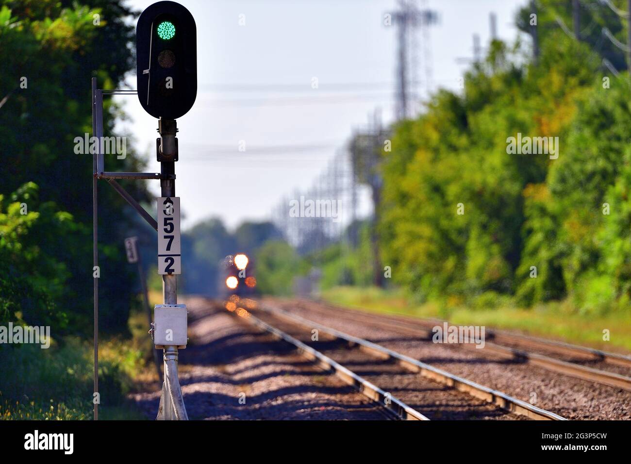 Genève, Illinois, États-Unis. Un signal vert permet aux trains de se rendre sur une voie tandis que les phares d'un train annoncent l'arrivée d'un train sur une autre voie. Banque D'Images