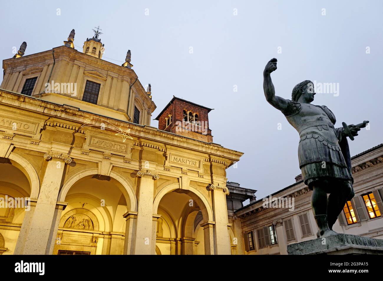 La statue de l'empereur romain Constantine et de l'église romaine Saint Lorenzo illuminée la nuit, à Milan. Italie. Banque D'Images