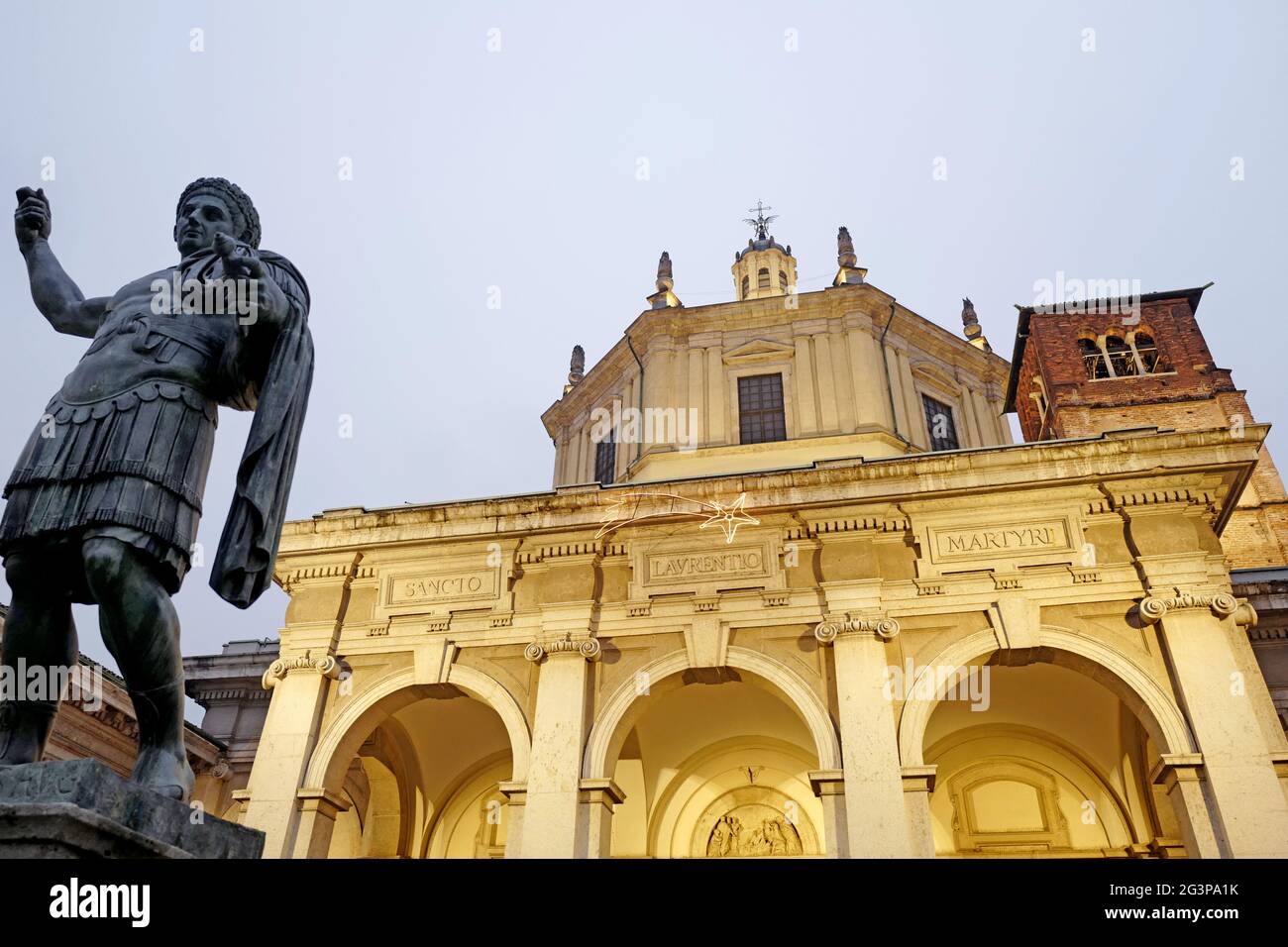 La statue de l'empereur romain Constantine et de l'église romaine Saint Lorenzo illuminée la nuit, à Milan. Italie. Banque D'Images