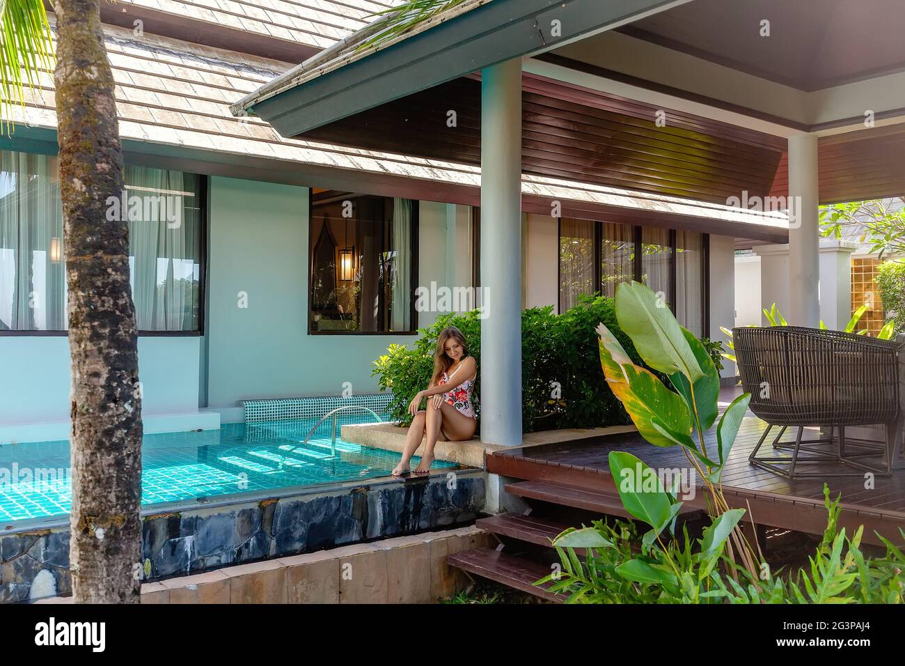 Jeune femme en tenue de bain assis près de la piscine sur Tropical Villa de luxe Banque D'Images