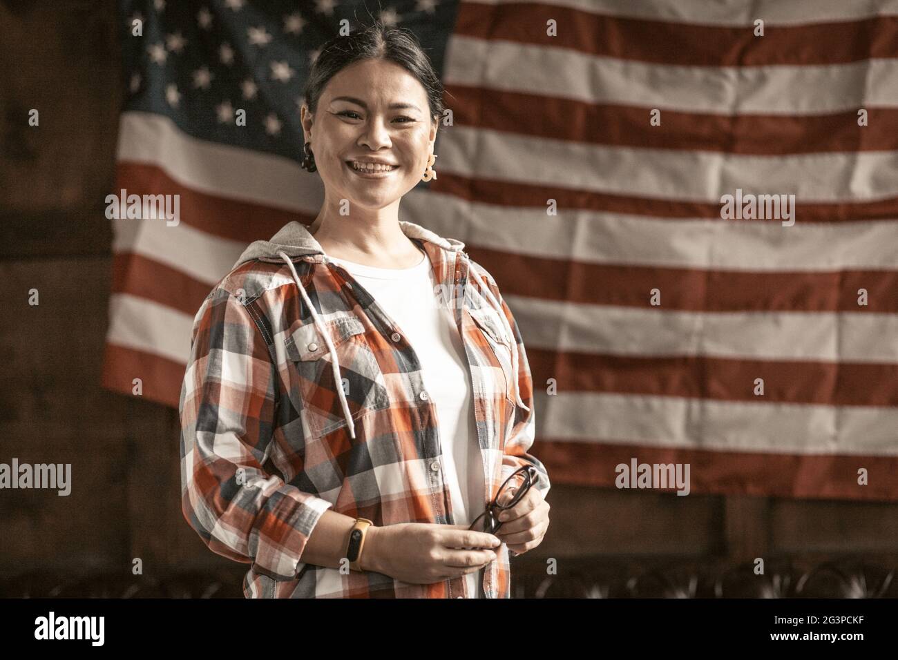 Femme asiatique souriante posant fièrement sur le drapeau de l'Amérique rayé de retour Banque D'Images