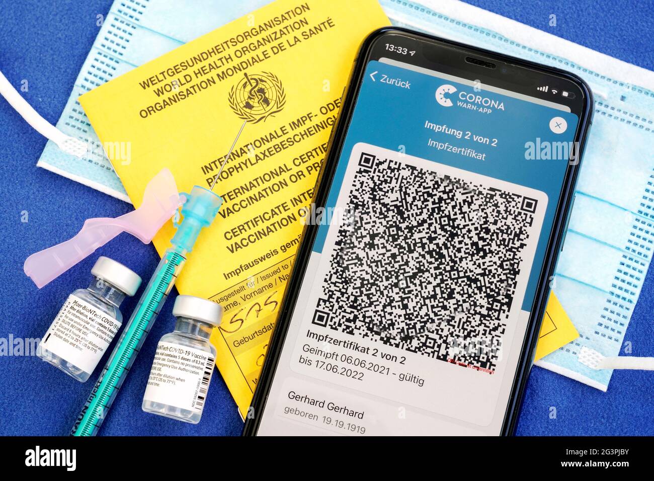 QR-Code, das digitale Impfzertifikat in der Corona warn-App auf einem smartphone bestätigt eine abgeschlossenen Impfung gegen Covid-19. Liegt auf dem gelben Internationalen Impfbescheinigung, Impfpass. - ACHTUNG! QR-Code und persönliche Angaben sind unkenntlich gemacht! Banque D'Images