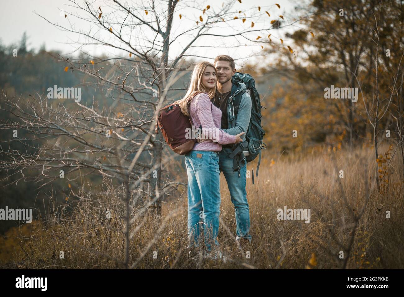 Couple souriant avec sacs à dos debout embrassés Banque D'Images