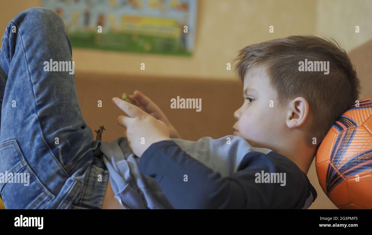 L'enfant regarde le téléphone allongé sur la table Banque D'Images