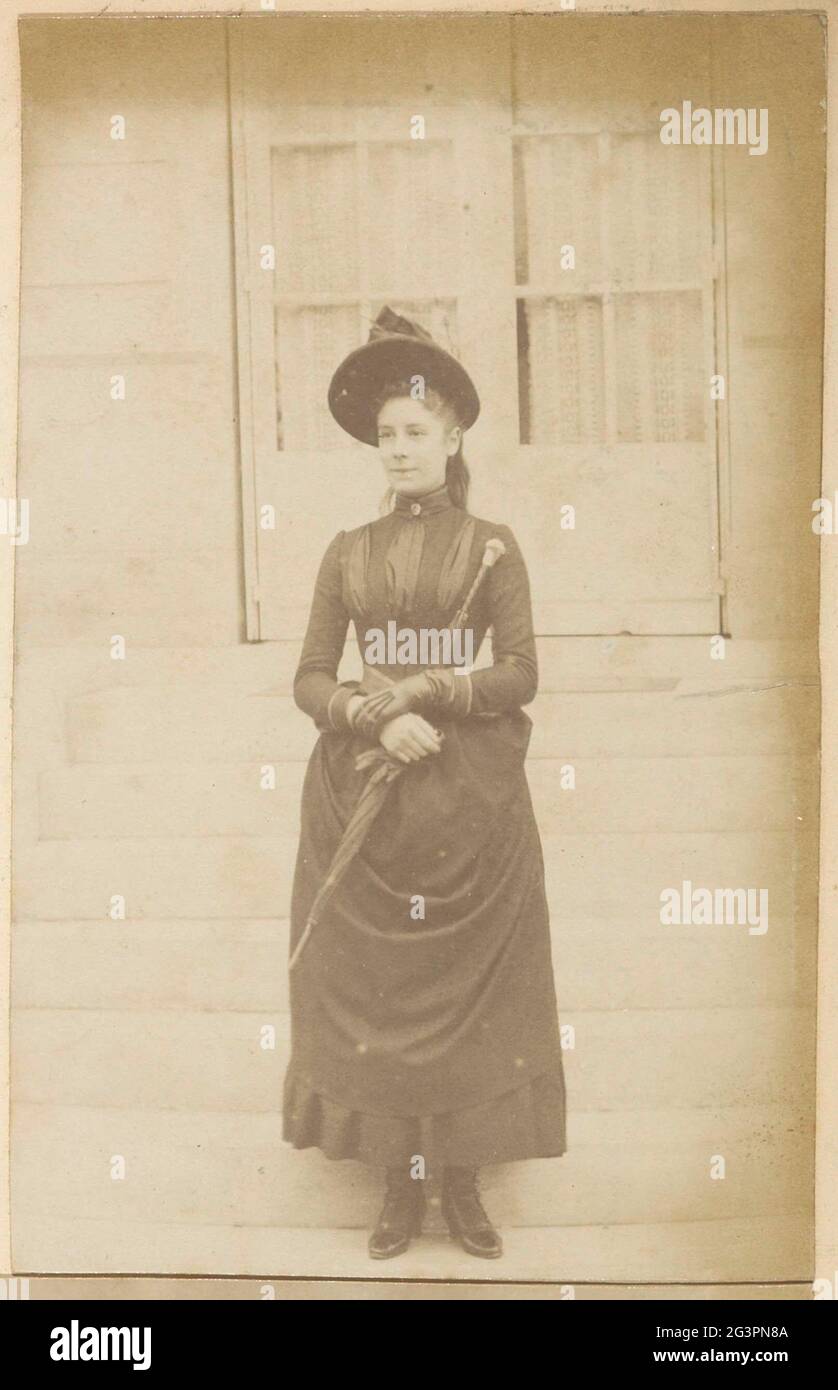 Portrait d'une fille française avec chapeau et parapluie, debout sur les  escaliers d'une maison. Partie d'un album photo d'un photographe amateur  français avec des enregistrements d'une famille, Distillery Delizy & Doakau  fils,