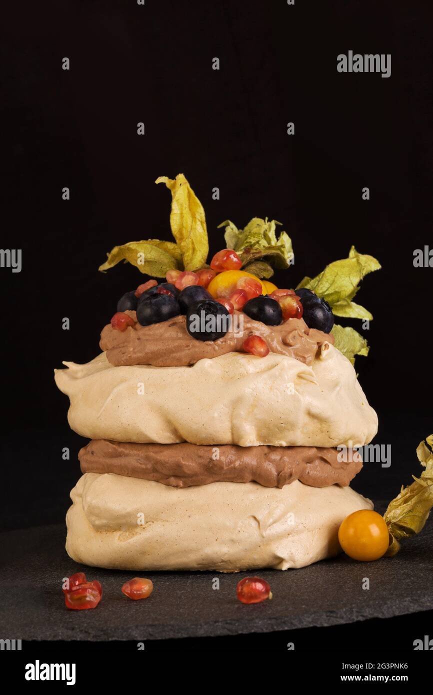 Gâteau Pavlova avec mélange de fruits sur noir. Banque D'Images