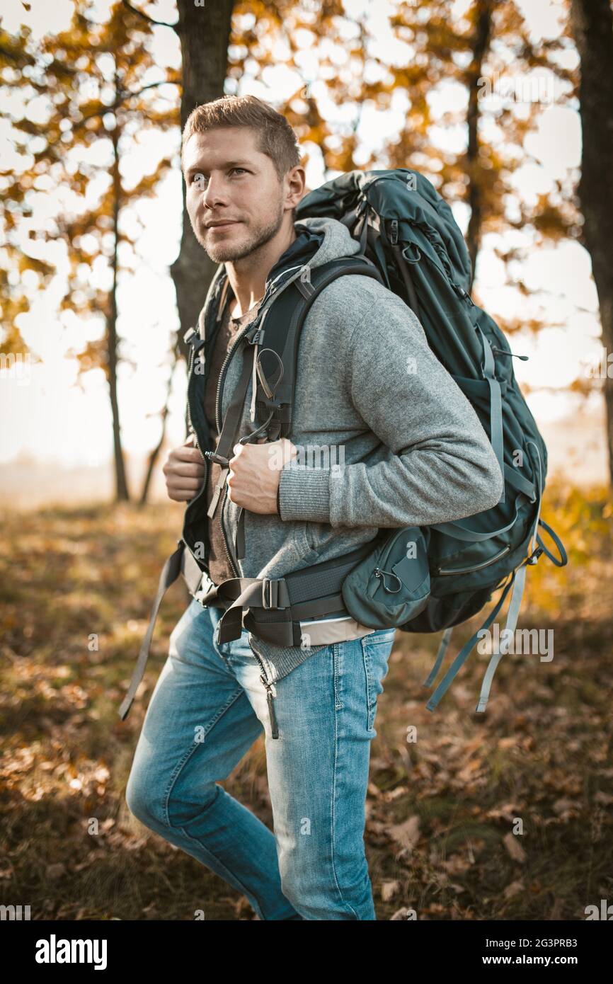 Backpacker voyage dans la nature. Un homme caucasien sérieux avec un grand sac à dos regarde dans la distance tout en se tenant contre le bac Banque D'Images