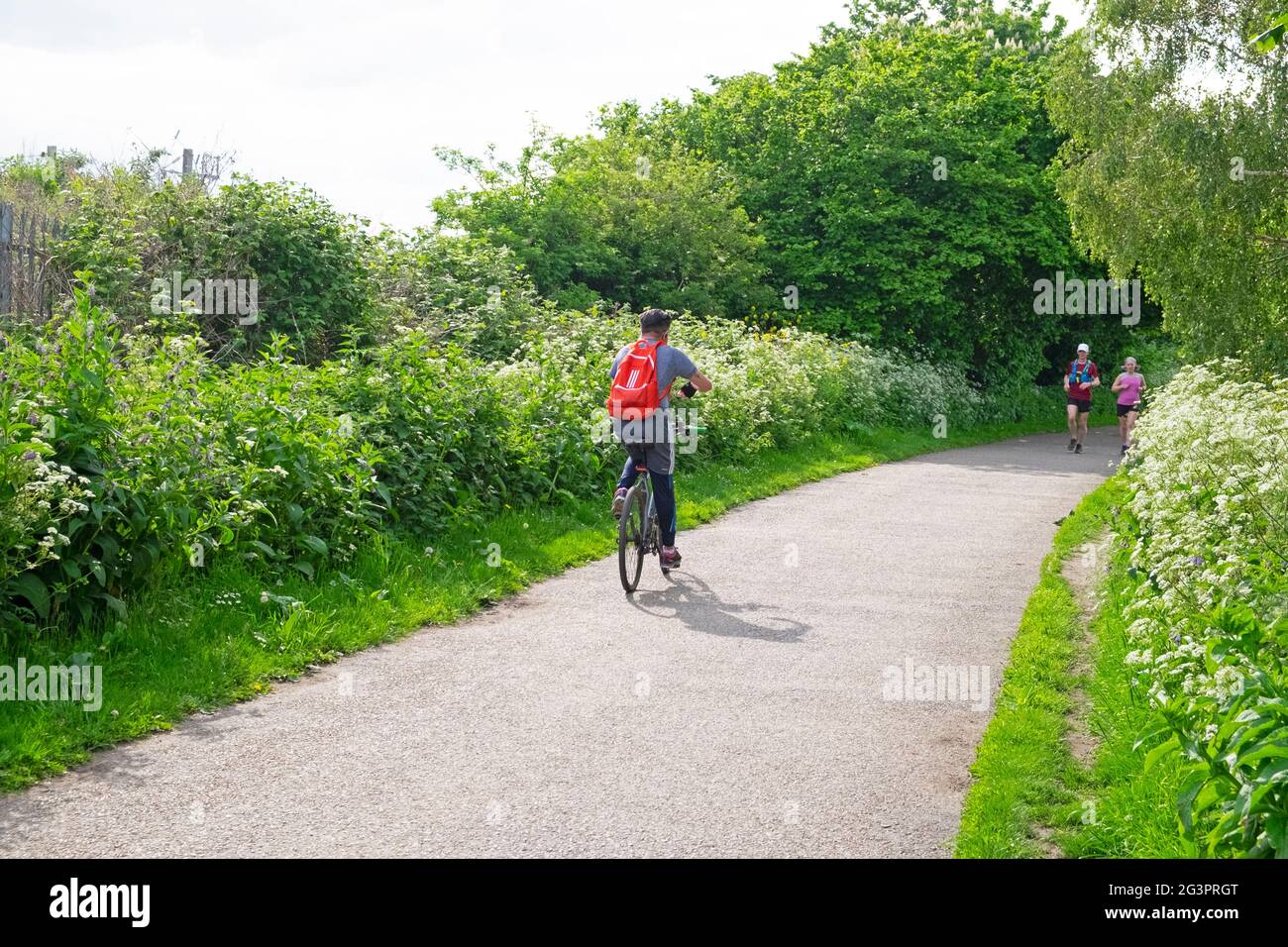 Cycliste sur un sentier de campagne dans la réserve naturelle de Walthamstow Wetlands et des personnes qui font du jogging au printemps Londres N17 Angleterre KATHY DEWIT Banque D'Images