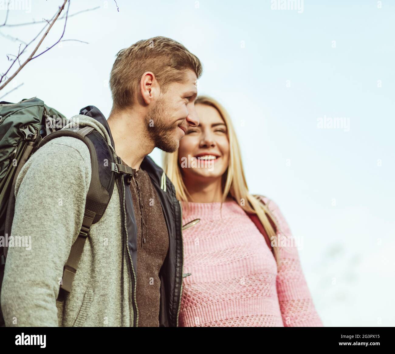 Deux touristes souriant tout en s'embrassant contre un ciel bleu. Accent sélectif sur la vue de profil du jeune homme caucasien WIT Banque D'Images