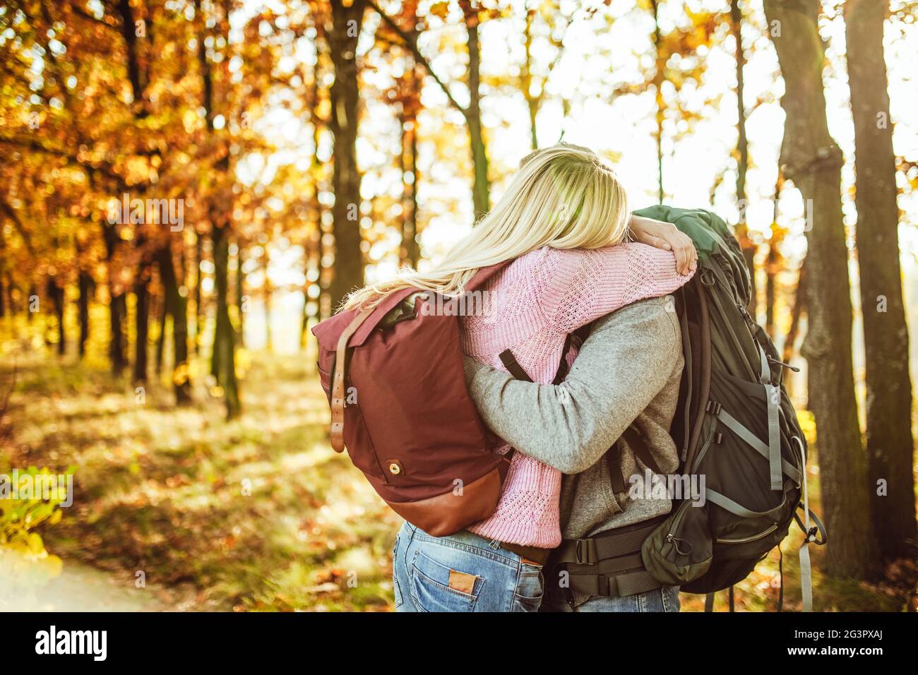 Choisissez entre deux voyageurs, homme et femme, avec des sacs à dos qui s'embrassent tout en se tenant dans la forêt d'automne. Copier l'espace à la dsri gauche Banque D'Images
