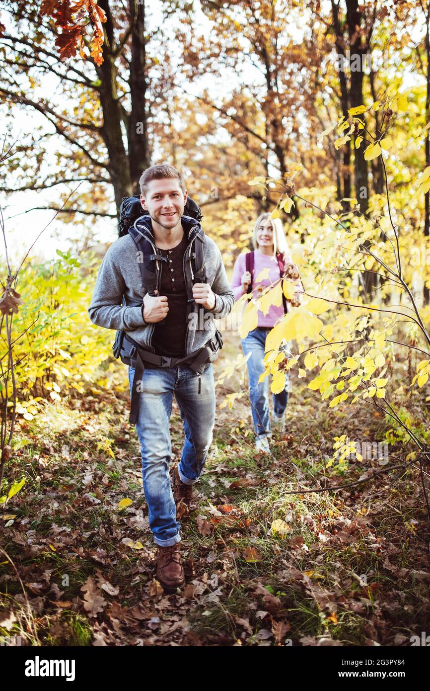 Couple de touristes amoureux voyage dans la nature d'automne. Concentrez-vous sur le jeune homme souriant caucasien avec un grand sac à dos en premier plan, Banque D'Images